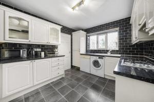 een keuken met witte kasten en een wasmachine en droger bij Spacious 3 bedrooms house in Bolton Upon Dearne Up to 6 Guests! 