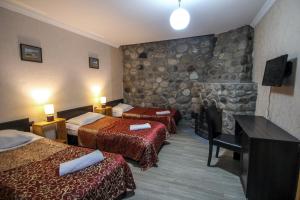 una camera d'albergo con due letti e una parete in pietra di Hotel Svaneti a Mestia