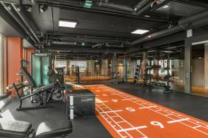 un gimnasio con máquinas de ejercicio en un suelo naranja en Ten Hotel BW Signature Collection, en Upplands-Väsby