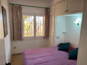 une chambre avec un lit violet et une fenêtre dans l'établissement CA LA CRISTI - 2 terrazas, piscina, wifi y barbacoa, à L'Escala