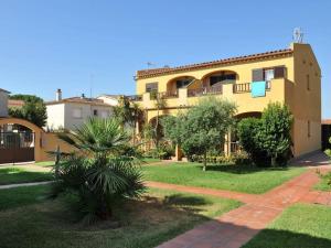 un grand bâtiment jaune avec une cour verdoyante dans l'établissement CA LA CRISTI - 2 terrazas, piscina, wifi y barbacoa, à L'Escala