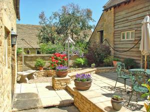 a patio with a table and chairs and flowers at Cotswold Charm Stable Cottage in Chipping Campden