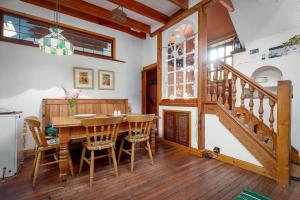 a dining room with a wooden table and a staircase at The Granary - Quaint & Cosy Cottage in Boarhills
