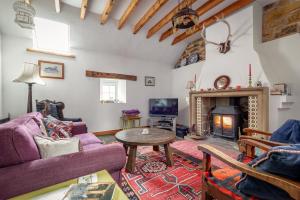 a living room with a couch and a table and a fireplace at The Granary - Quaint & Cosy Cottage in Boarhills