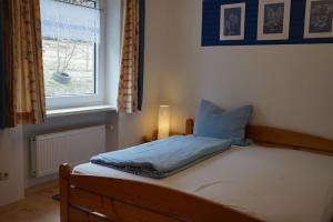 un letto con un cuscino blu e una finestra di Ferienhaus Napoleon a Waldmünchen