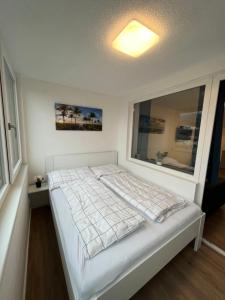 ein weißes Bett in einem Zimmer mit Fenster in der Unterkunft Modernes 4er Apartment in Skilift-Nähe in Zell am See