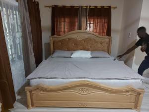 a man is cleaning a bed in a bedroom at Masbella Airbnb in Kumasi