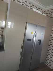 frigorifero in acciaio inossidabile in una stanza con muro di mattoni di Masbella Airbnb a Kumasi