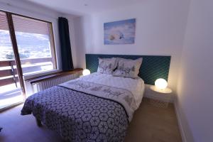 a bedroom with a bed and a large window at Duplex 65 m2 au coeur du golf de Tignes in Tignes