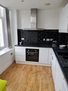 uma cozinha com armários brancos e electrodomésticos pretos em Luxury 2 Bedroom, and 2 Bathroom Apartment em Cardiff