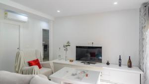 uma sala de estar branca com uma televisão e duas cadeiras em Casa Ana de Guaro by Ruralidays em Guaro