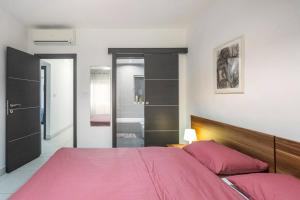 a bedroom with a pink bed and a walk in shower at Beblow flats in Sliema