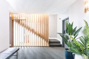 a hallway with a wooden pivot door with plants at ELEVEN Real de la Carretería, by Homing U in Seville