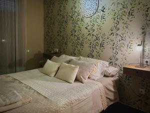 Schlafzimmer mit einem Bett mit weißer Bettwäsche und Blumentapete in der Unterkunft GIRALDA 2 in Ponteareas