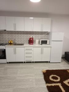 uma cozinha com armários brancos e um aparelho vermelho em apartament de lux em Lupeni