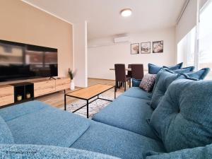 ein Wohnzimmer mit einem blauen Sofa und einem TV in der Unterkunft St. Antoni Suite 5 in Eisenstadt