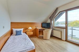 a hotel room with a bed and a desk and a window at Hotel Café Ernst in Bernkastel-Kues