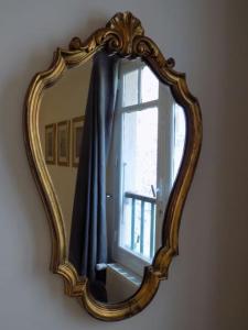 a mirror hanging on a wall with a window at L'ancienne Forge - a stylish medieval holiday home in Confolens