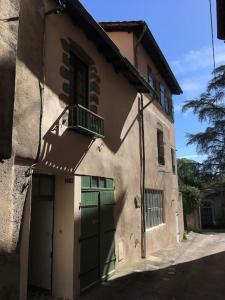 a building with a green door and a balcony at L'ancienne Forge - a stylish medieval holiday home in Confolens
