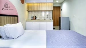 a bedroom with a white bed and a kitchen at Kozii Room at Evenciio Apartment in Pondokcina