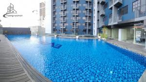 a large blue swimming pool in front of a building at Kozii Room at Evenciio Apartment in Pondokcina