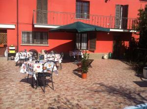 eine Terrasse mit Tischen und einem Sonnenschirm vor einem roten Gebäude in der Unterkunft Agriturismo e Az. Agricola Ma.Mi in Sale