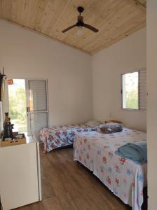 1 dormitorio con 2 camas y ventilador de techo en CHALÉS MARICOTA, en Vargem Bonita