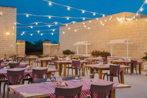 a row of tables and chairs on a patio with lights at Relais Masseria Le Cesine - CDSHotels in Vernole