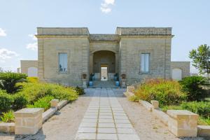 un edificio in pietra con un sentiero che conduce a una porta di Relais Masseria Le Cesine - CDSHotels a Vernole