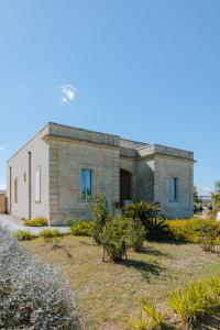 uma casa de tijolos com janelas azuis num quintal em Relais Masseria Le Cesine - CDSHotels em Vernole