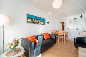 ein Wohnzimmer mit einem schwarzen Sofa und einer Küche in der Unterkunft Blankwasserweg 131 Lensterstrand Oase Bungalow 2 in Lenste