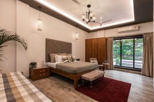 罗纳瓦拉SaffronStays Uno Crest, Lonavala - 4 BDR Artistically Decorated Villa Near Bhushi Dam的一间带床和大窗户的卧室