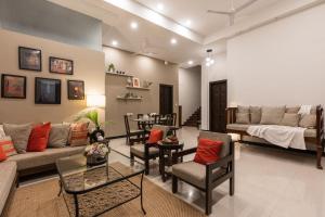 罗纳瓦拉SaffronStays Uno Crest, Lonavala - 4 BDR Artistically Decorated Villa Near Bhushi Dam的带沙发、椅子和桌子的客厅