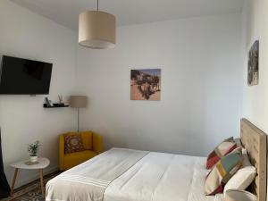 a bedroom with a bed and a yellow chair at Casa de las Especias Hotel Boutique in Sanlúcar de Barrameda