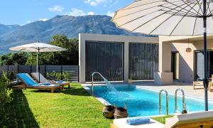 un patio trasero con piscina con sombrilla en KS Luxury Villas Heated Pools, en Georgioupolis
