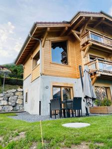 a house with a table and chairs and an umbrella at Gîte Au Balcon de Passy/Plaine Joux, classé 2 ** in Passy