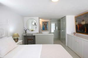 a white bedroom with a white bed and a mirror at Villa Aphrodite · Elegant villa, sea views, designer renovation in Ambelas +30 photos