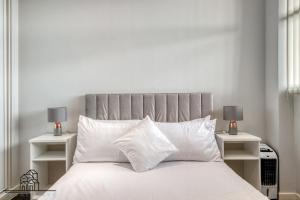 um quarto com uma cama branca com duas mesas de cabeceira em Cosy 1-Bed by Heathrow Airport em Londres