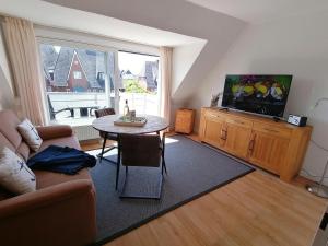 ein Wohnzimmer mit einem Sofa, einem Tisch und einem TV in der Unterkunft Sylter Finke Appartement in Wenningstedt-Braderup