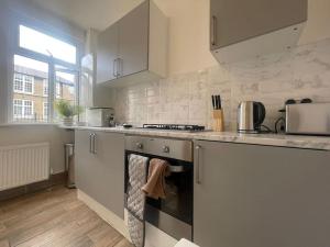 a kitchen with white cabinets and a stove top oven at Cosy 2 Bed in Tower Bridge Road in London