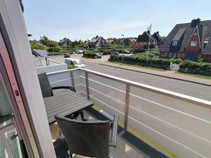 einen Balkon mit 2 Stühlen und Straßenblick in der Unterkunft Sylter Finke Appartement in Wenningstedt-Braderup