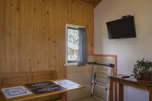 a room with a table and a tv and a window at Cabañas Tierra Nueva in Curarrehue