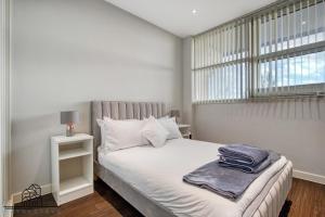 een witte slaapkamer met een bed en een raam bij Cosy 1-Bed by Heathrow Airport in Londen