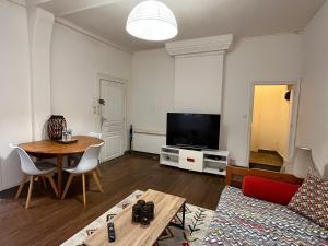 uma sala de estar com uma mesa e uma televisão em Jupiter YourHostHelper em Caen