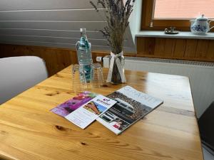 una mesa de madera con una botella de agua y una revista en Pension Grandel, en Kottmar