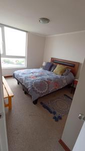 a bedroom with a bed and a large window at Papudo Laguna, Hermoso Apartamento junto al Mar in Papudo