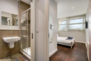 a bathroom with a sink and a shower and a bed at Cosy 1-Bed by Heathrow Airport in London