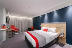 バーンリーにあるHoliday Inn Express Burnley M65 Jct 10, an IHG Hotelのベッドと赤い椅子が備わるホテルルームです。