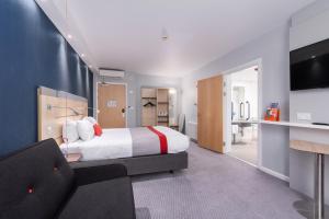 バーンリーにあるHoliday Inn Express Burnley M65 Jct 10, an IHG Hotelのベッドとソファ付きのホテルルーム
