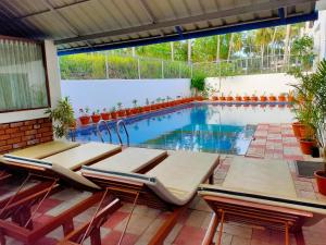 a swimming pool with two lounge chairs and a table at Dr Nisha's Vedic Remedies in Trivandrum